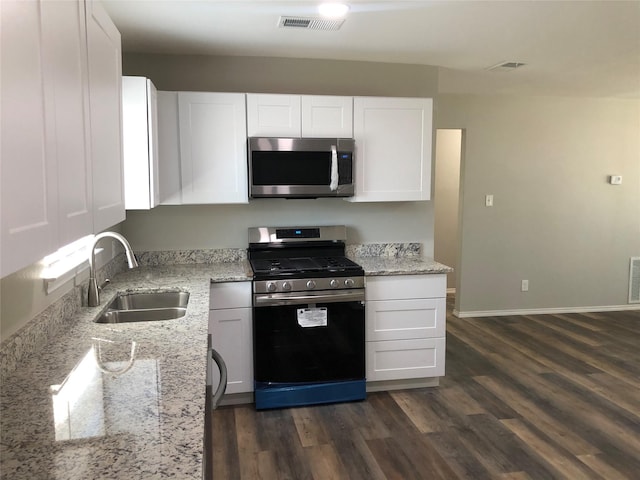 kitchen with visible vents, a sink, light stone counters, white cabinets, and stainless steel appliances