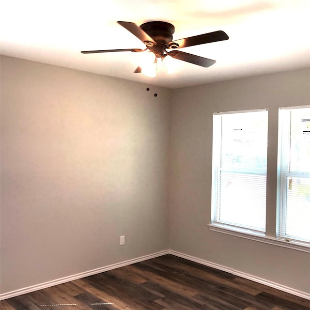 spare room with baseboards, ceiling fan, and dark wood-type flooring