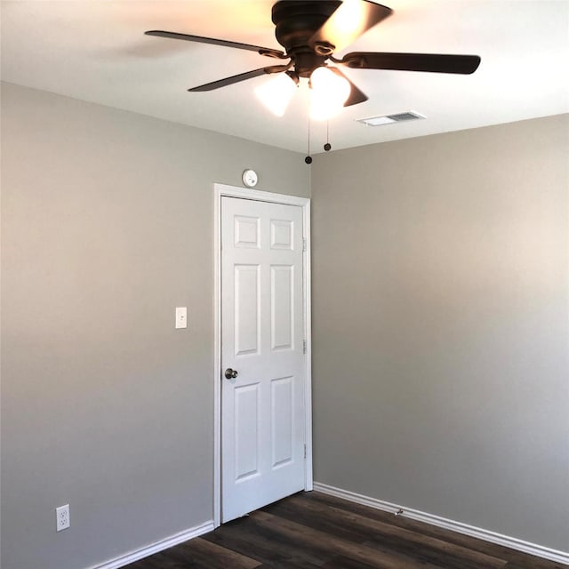 spare room with baseboards, a ceiling fan, dark wood finished floors, and visible vents