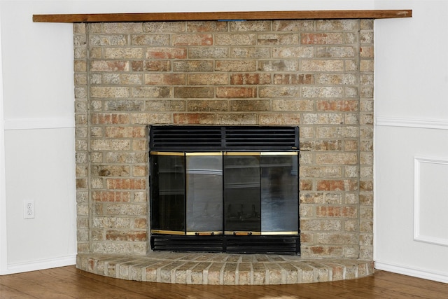 details with baseboards, a brick fireplace, and wood finished floors