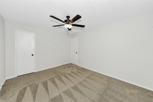 carpeted spare room with baseboards and ceiling fan