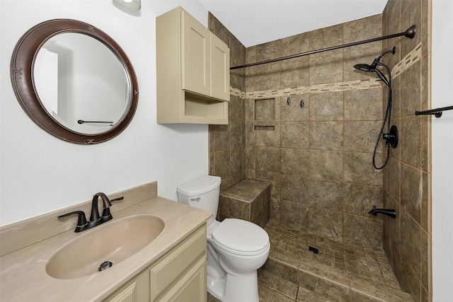 bathroom featuring vanity, toilet, and tiled shower