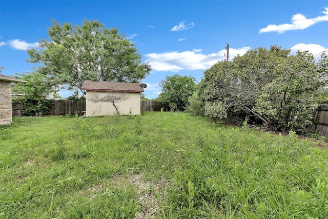 view of yard featuring an outbuilding, a fenced backyard, and a storage shed