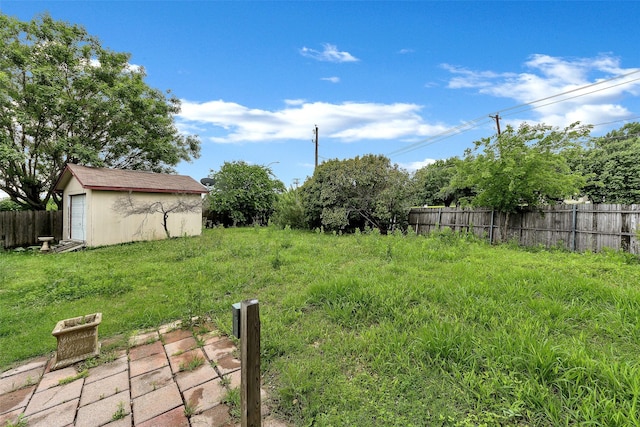 view of yard featuring a storage shed, fence, and an outdoor structure