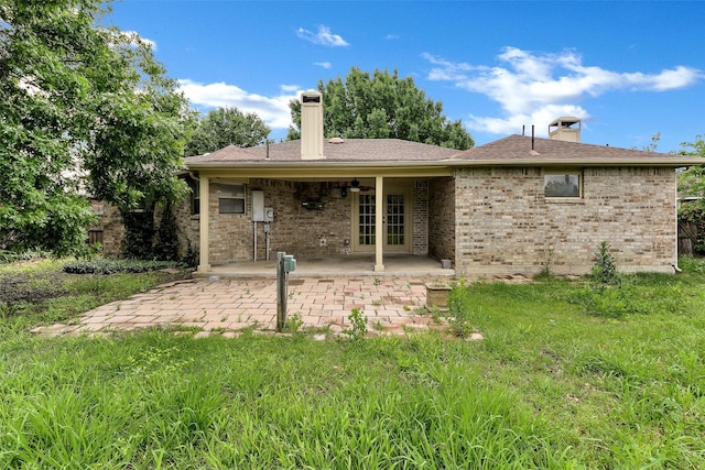 back of house featuring french doors, a chimney, a patio area, and brick siding