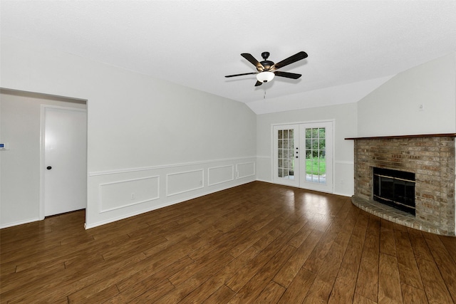 unfurnished living room with french doors, a ceiling fan, wainscoting, a brick fireplace, and wood finished floors