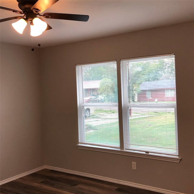empty room featuring baseboards, dark wood finished floors, and ceiling fan