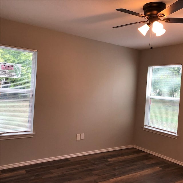 spare room with a ceiling fan, baseboards, dark wood-style floors, and a healthy amount of sunlight