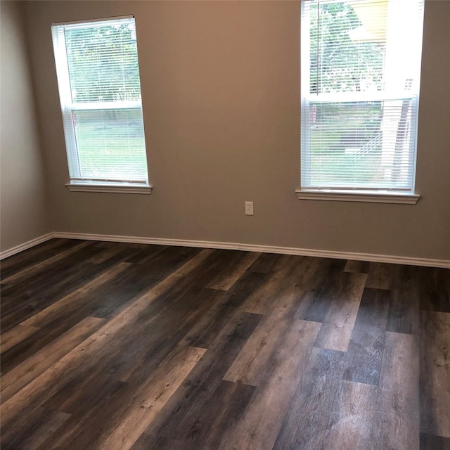 unfurnished room with baseboards and dark wood-style flooring