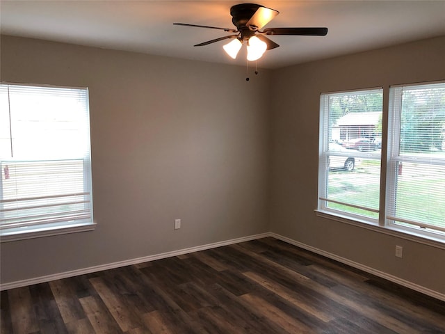 spare room with baseboards, a ceiling fan, and dark wood finished floors