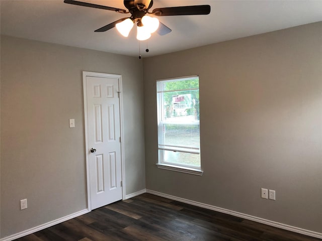 empty room with baseboards, ceiling fan, and dark wood-style floors