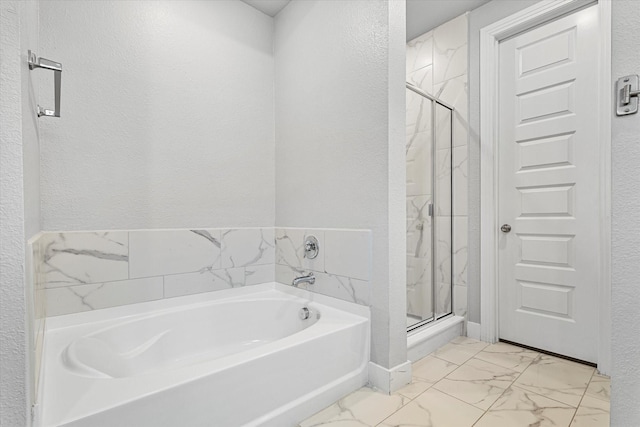 bathroom with a garden tub, marble finish floor, a textured wall, and a marble finish shower