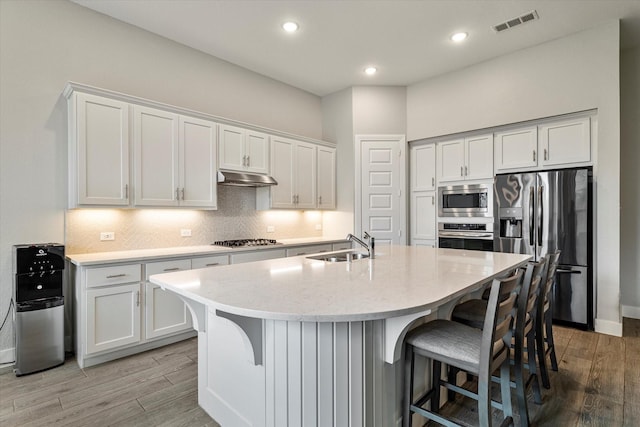 kitchen featuring light countertops, light wood-style floors, stainless steel appliances, and under cabinet range hood