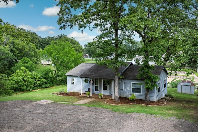 view of front of property featuring a storage unit, an outbuilding, covered porch, and a front lawn