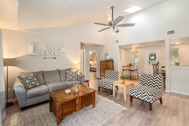 living room with high vaulted ceiling, a ceiling fan, wood finished floors, and visible vents