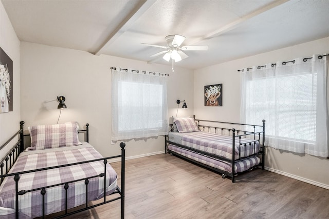 bedroom featuring baseboards, ceiling fan, multiple windows, and light wood-style flooring