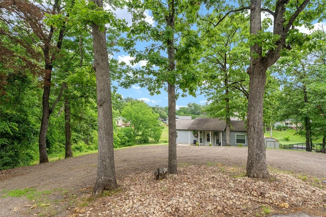 view of front facade with a storage shed, curved driveway, an outdoor structure, and fence