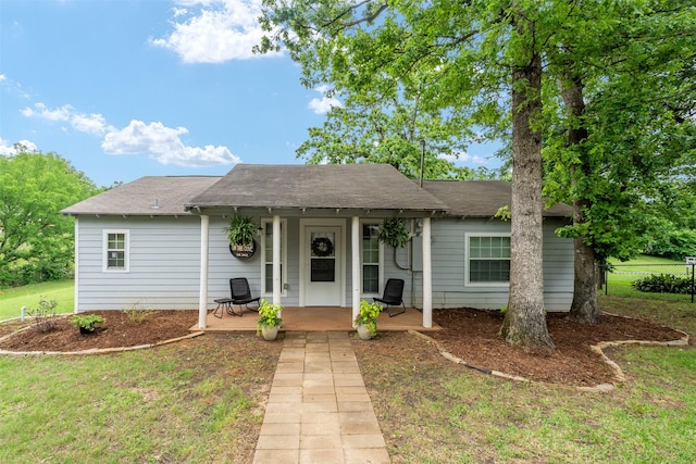 view of front of home featuring a shingled roof, a porch, and a front yard
