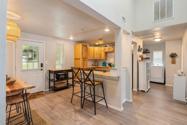 kitchen featuring baseboards, light wood-style flooring, independent washer and dryer, and visible vents
