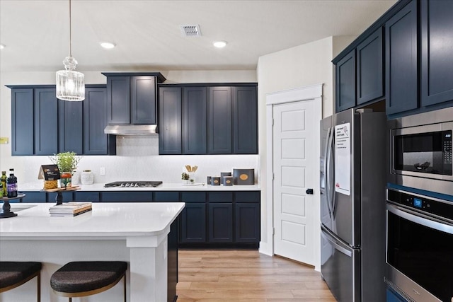 kitchen featuring a kitchen breakfast bar, pendant lighting, light wood-type flooring, light countertops, and stainless steel appliances