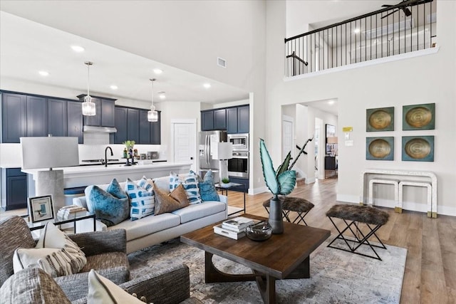 living room featuring light wood-style floors, baseboards, recessed lighting, and visible vents