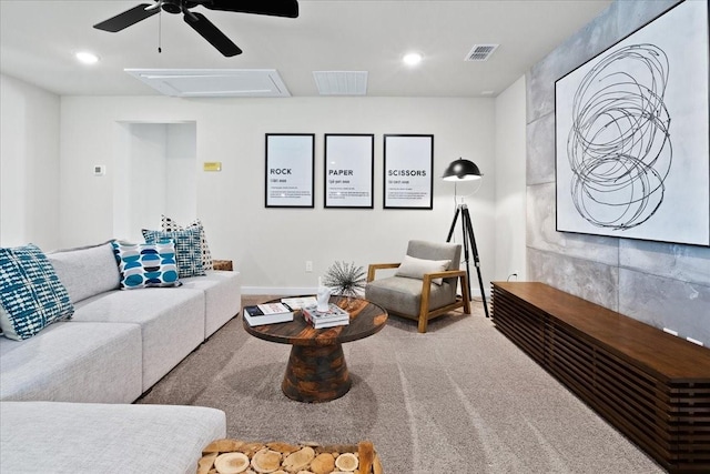 living area with carpet floors, ceiling fan, visible vents, and attic access