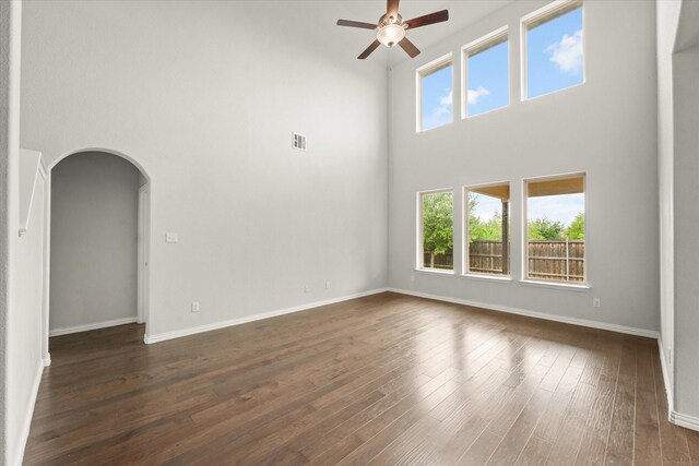 1617 Beauregard Point Dr, Wylie, TX 75098 - unfurnished living room with visible vents, a towering ceiling, ceiling fan, dark wood-style floors, and arched walkways