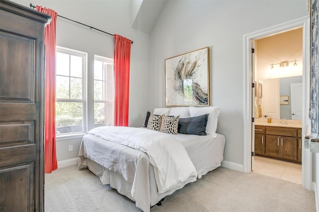 bedroom with a sink, baseboards, light carpet, and ensuite bath