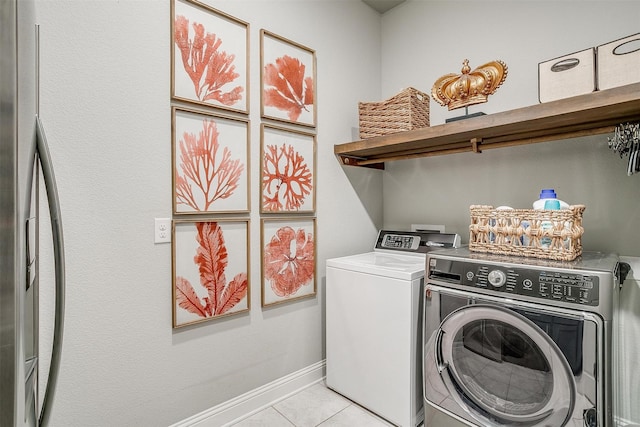 clothes washing area featuring light tile patterned floors, baseboards, laundry area, and washer and dryer