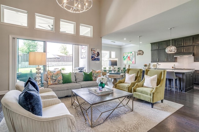 living area with a towering ceiling, dark wood-style flooring, and a notable chandelier