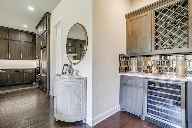bar with dark wood-style flooring, wine cooler, baseboards, a dry bar, and backsplash
