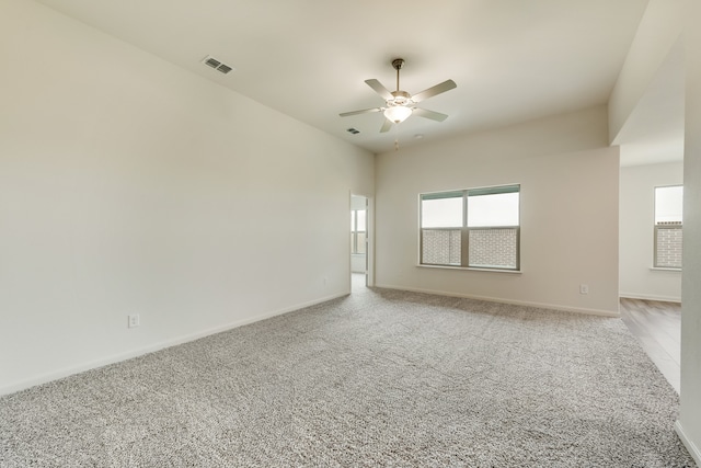 unfurnished room with visible vents, a ceiling fan, baseboards, and light colored carpet
