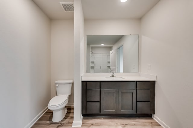 bathroom featuring visible vents, vanity, wood finished floors, toilet, and baseboards