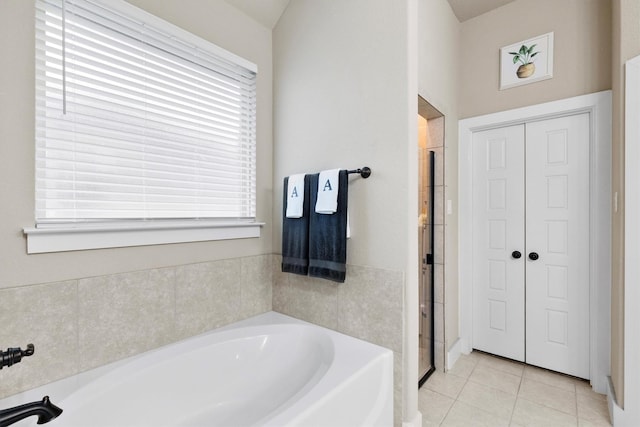bathroom featuring tile patterned flooring, a garden tub, and a shower stall