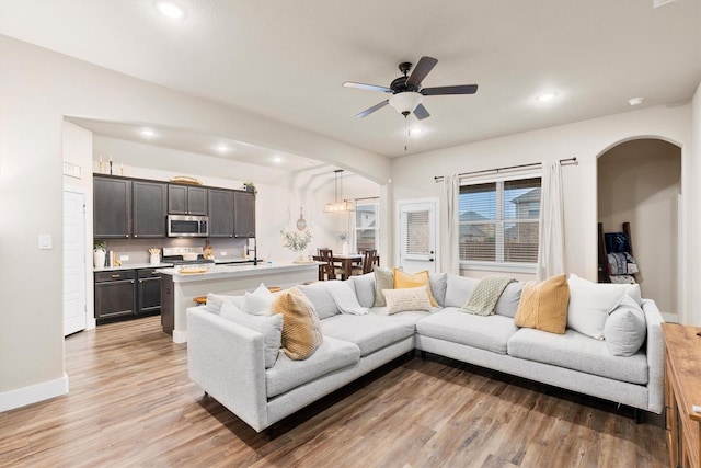 living area with arched walkways, recessed lighting, and light wood-style flooring