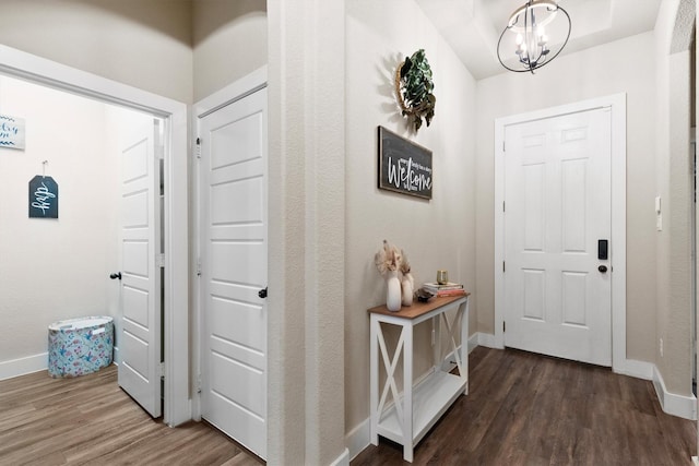 entryway featuring baseboards, wood finished floors, and a notable chandelier