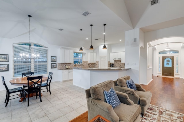 living room with arched walkways, a notable chandelier, and visible vents