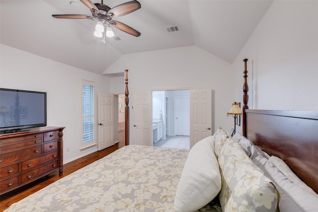 bedroom featuring ceiling fan, visible vents, vaulted ceiling, wood finished floors, and ensuite bathroom