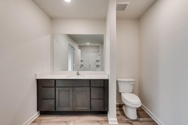 bathroom with baseboards, toilet, wood finished floors, and visible vents