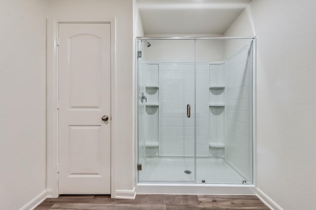 bathroom featuring baseboards, wood finished floors, and a stall shower