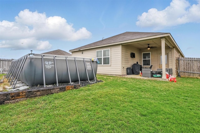 back of property featuring a ceiling fan, a patio area, and a swimming pool