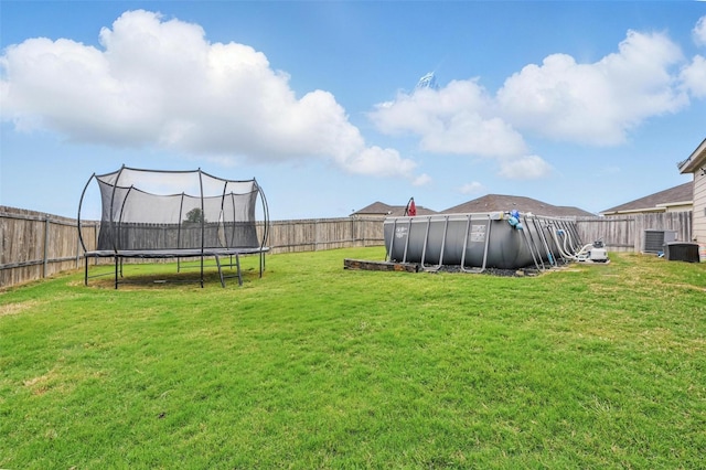view of yard with a trampoline and central AC unit