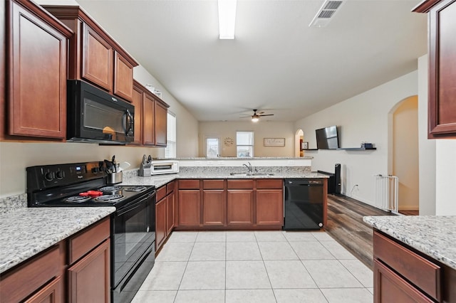 kitchen featuring black appliances, arched walkways, a ceiling fan, a peninsula, and a sink