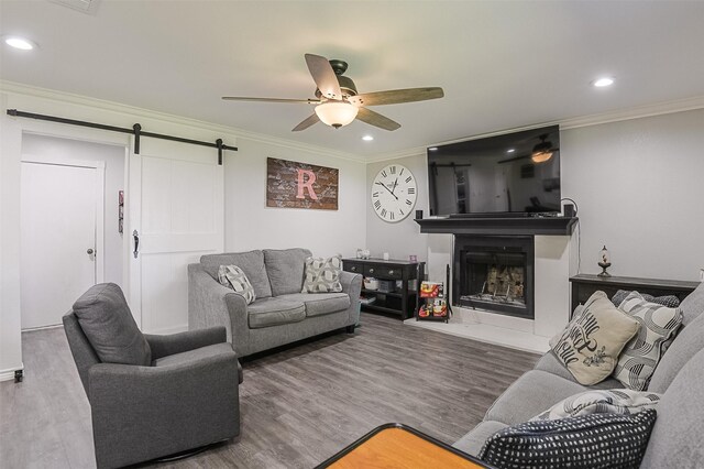 dining space featuring crown molding, a fireplace with raised hearth, a ceiling fan, and wood finished floors