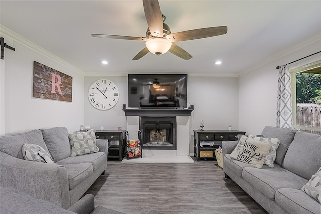 living room with recessed lighting, a fireplace with raised hearth, a ceiling fan, and wood finished floors