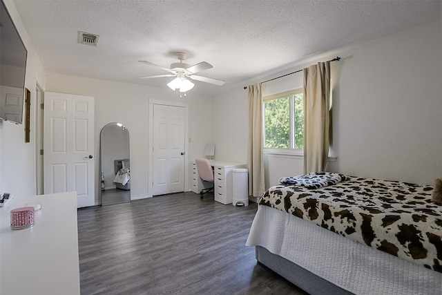 bedroom with visible vents, a textured ceiling, dark wood-style flooring, and ceiling fan