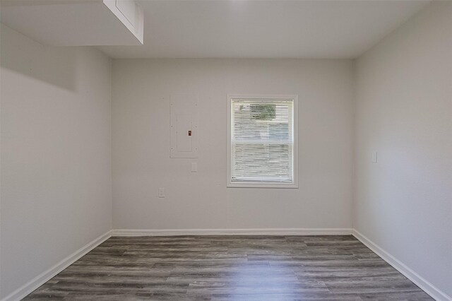 spare room with baseboards and dark wood-type flooring