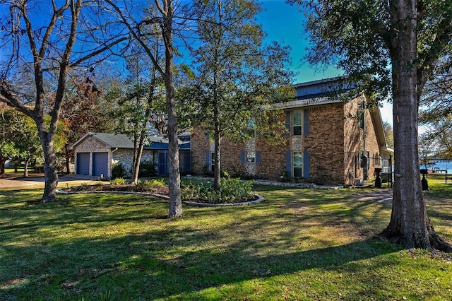 view of front of house featuring brick siding, a garage, driveway, and a front lawn