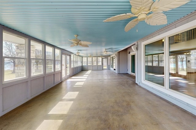 unfurnished sunroom featuring a ceiling fan and concrete flooring