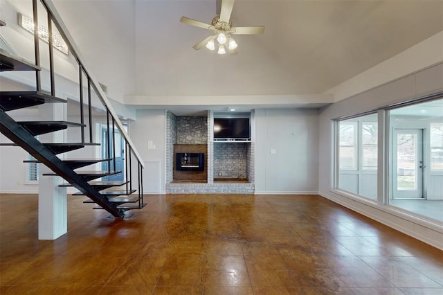 unfurnished living room featuring a large fireplace, stairs, a ceiling fan, baseboards, and a towering ceiling